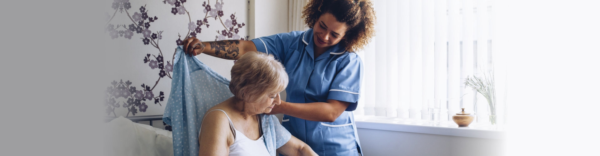 caregiver helping a senior woman get dressed